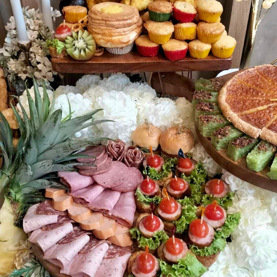 A variety of foods arranged on a table for a grazing table setup, including cheeses, cold cuts, fruits, nuts, and kakanin.