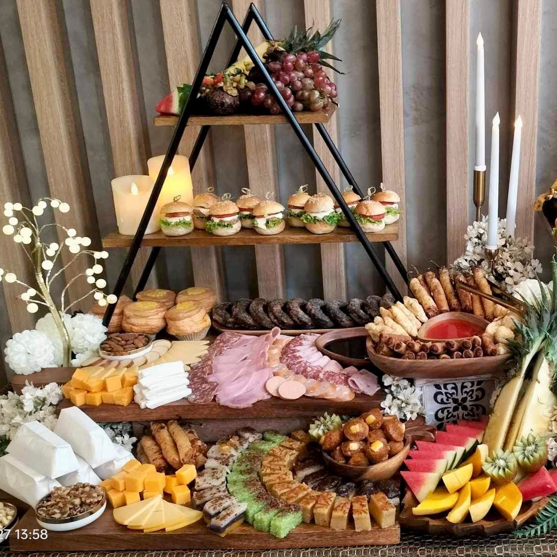 A variety of foods arranged on a table for a grazing table setup, including cheeses, cold cuts, fruits, nuts, and kakanin.